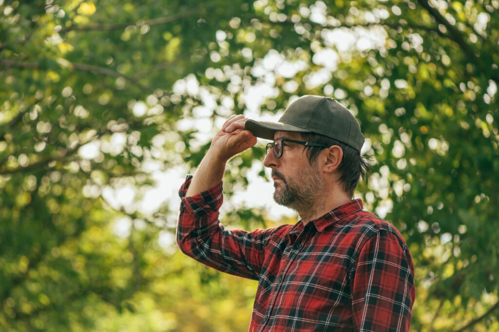 Portrait of male farmer in walnut fruit orchard looking at trees